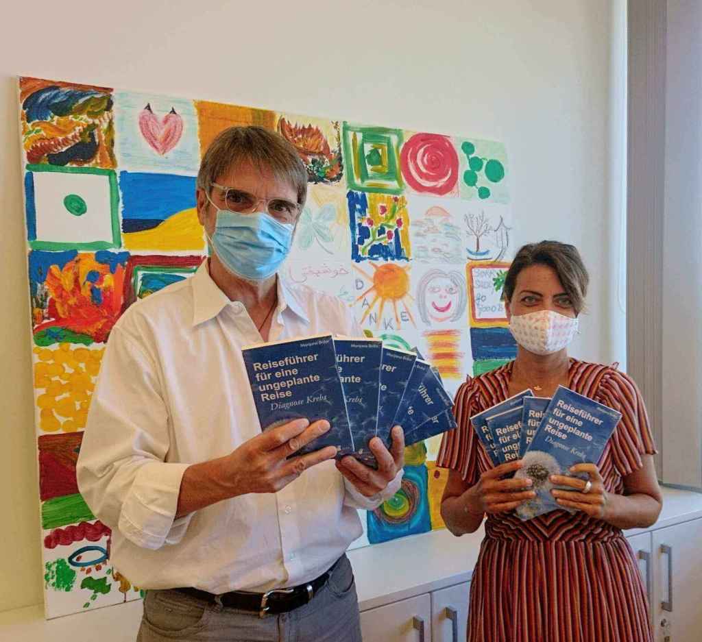 Marijana Brdar zeigt sich Mund- und Nasenschutz bezüglich ihrer Buchspende. Sie hält 3 Bücher in der Hand.